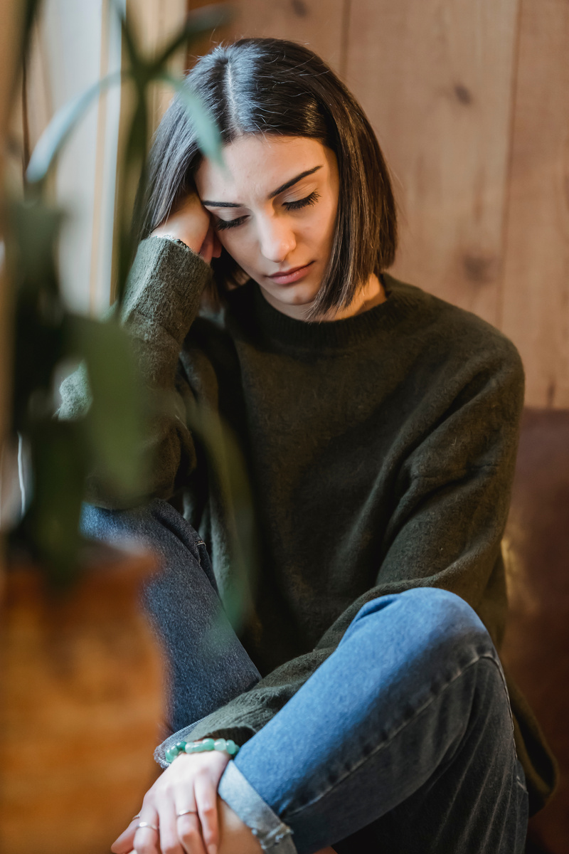 Tired woman sitting in solitude near window